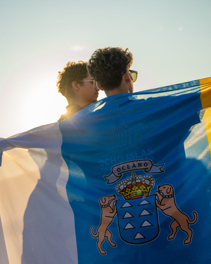 Dos miembros del equipo envueltos en la bandera de Canarias a contraluz