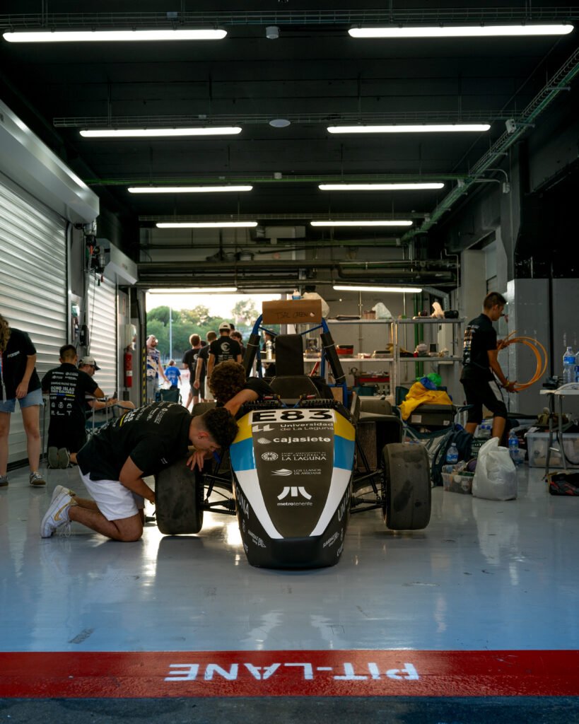 Monoplaza dentro del box con un mecánico trabajando junto a la línea del pit lane