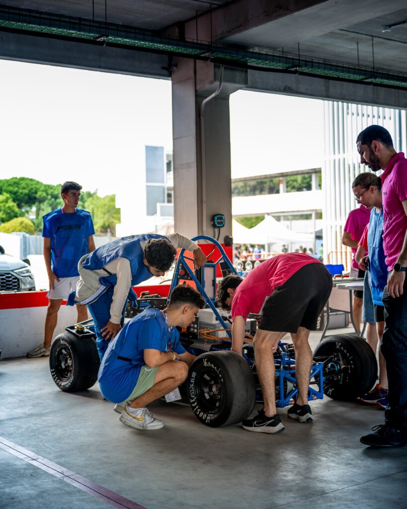 Equipo trabajando sobre el chasis azul del monoplaza en el box